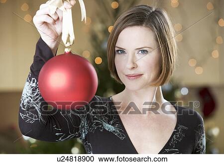 Stock Image - A woman holding a Christmas decoration. Fotosearch