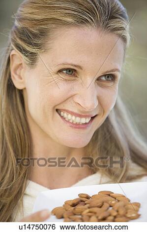 Stock Photograph - A woman holding a dish of almonds. Fotosearch