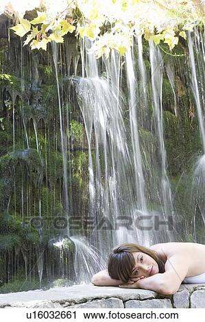 Stock Image - A woman relaxing by a waterfall. Fotosearch