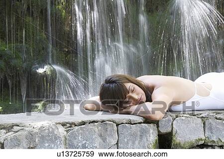 A woman relaxing by a waterfall View Large Photo Image Stock Photo - A woman relaxing by a waterfall. Fotosearch