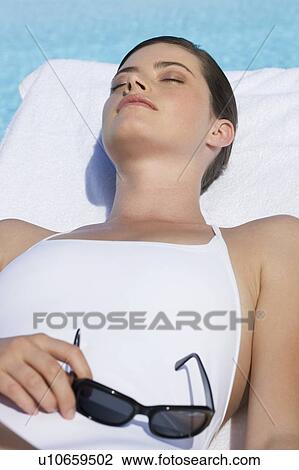 A woman sunbathing by a pool View Large Photo Image Stock Image - A woman sunbathing by a pool. Fotosearch