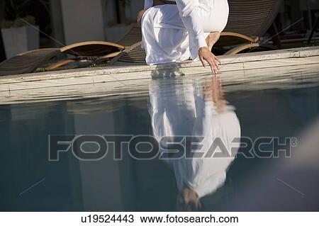 Stock Image - A woman testing the temperature of a swimming pool. Fotosearch