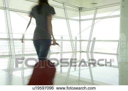 Stock Photograph - A woman walking through an airport. Fotosearch