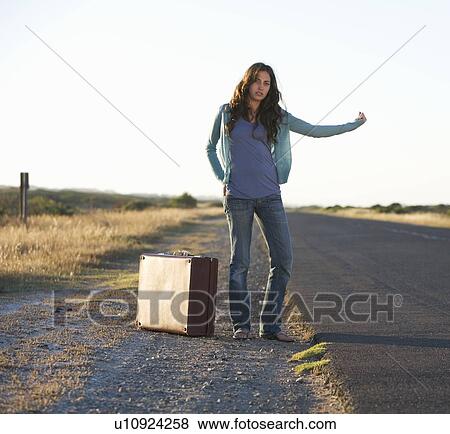 Stock Photo - A woman with a suitcase hitching a lift. Fotosearch