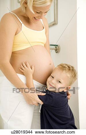 Picture - A young boy hugging his pregnant mother. Fotosearch