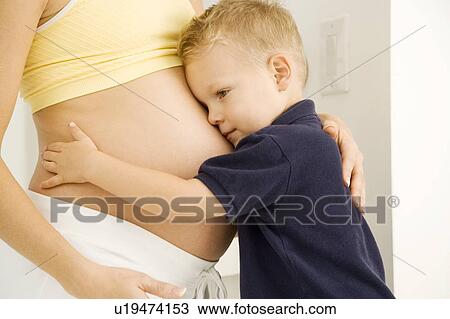 Stock Image - A young boy hugging his pregnant mother. Fotosearch