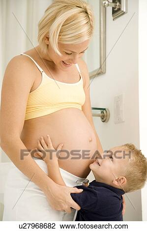 Stock Image - A young boy hugging his pregnant mother. Fotosearch