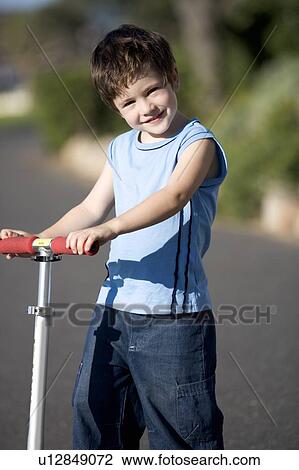 A young boy on a scooter View Large Photo Image Stock Image - A young boy on a scooter. Fotosearch