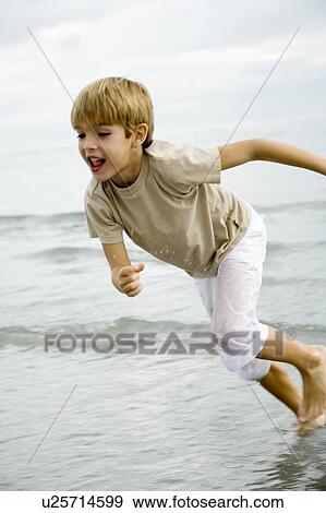 Stock Photo - A young boy running on a beach. Fotosearch