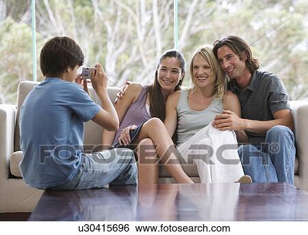 A young boy taking a photo of his family sitting on a sofa View Large Photo Image Stock Photograph - A young boy taking a photo of his family sitting on a sofa. Fotosearch