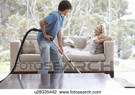 Stock Image - A young boy vacuuming whilst his mother relaxes. Fotosearch