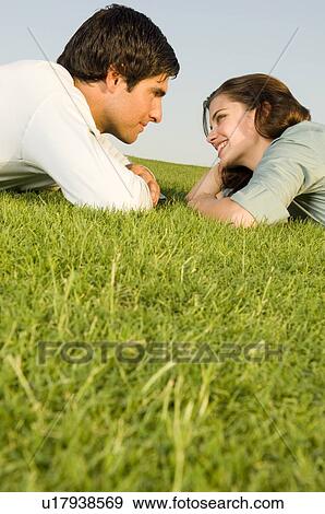 Stock Photo - A young couple laying on grass. Fotosearch