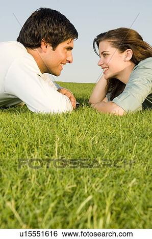 A young couple laying on grass View Large Photo Image Stock Photograph - A young couple laying on grass. Fotosearch
