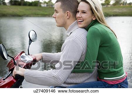 Stock Photograph - A young couple on a scooter. Fotosearch