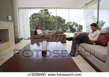 Stock Image - A young couple sitting in a living room. Fotosearch