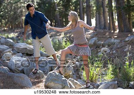 Stock Photo - A young couple walking over rocks. Fotosearch