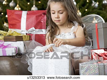 Stock Image - A young girl dressed as a fairy opening a Christmas present. Fotosearch