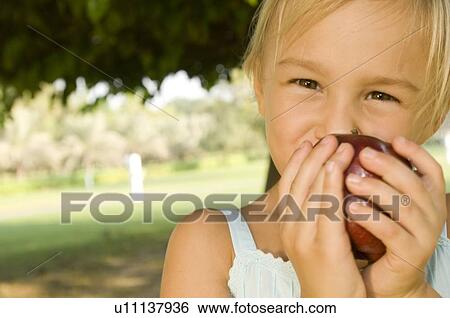 Stock Photograph - A young girl eating an apple. Fotosearch
