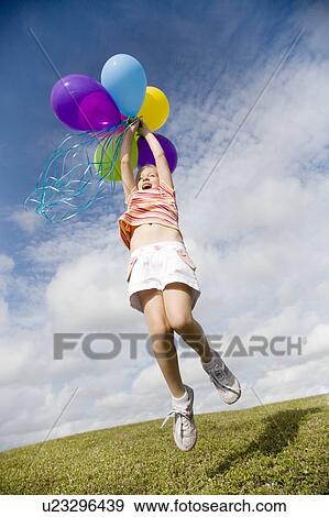 Stock Photo - A young girl holding a bunch of balloons. Fotosearch