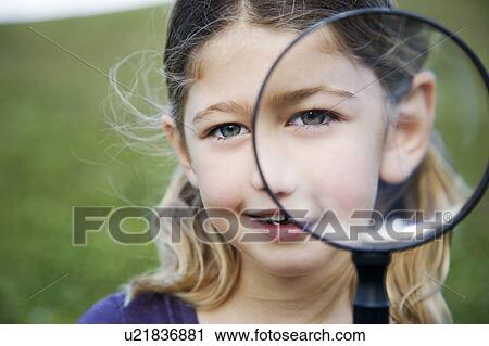 Stock Image - A young girl holding a magnifying glass. Fotosearch