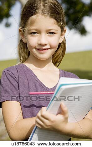 A young girl holding a notebook View Large Photo Image Stock Image - A young girl holding a notebook. Fotosearch