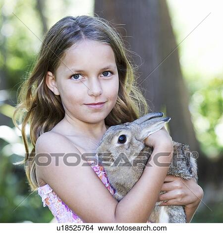 Picture - A young girl holding a pet rabbit, close-up. Fotosearch