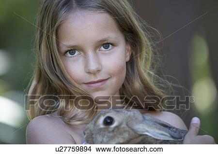 Picture - A young girl holding a pet rabbit, close-up. Fotosearch