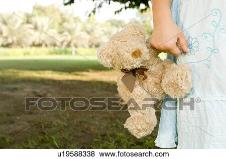 Stock Photo - A young girl holding a teddy bear. Fotosearch