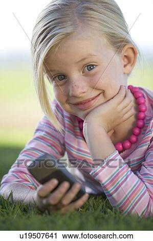 Stock Image - A young girl playing with a mobile phone. Fotosearch