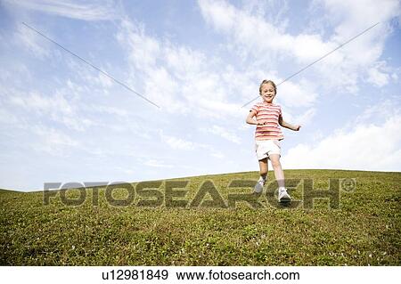 Stock Photo - A young girl running across a hill. Fotosearch