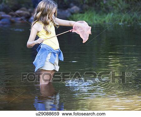 A young girl standing in a river with a fishing net View Large Photo Image Stock Photo - A young girl standing in a river with a fishing net. Fotosearch