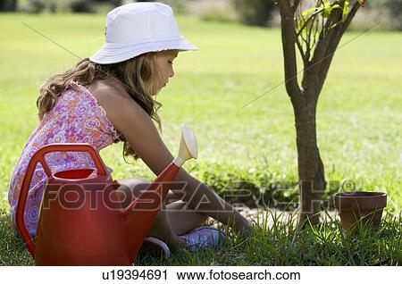 A young girl tending a plant in the garden View Large Photo Image Stock Image - A young girl tending a plant in the garden. Fotosearch