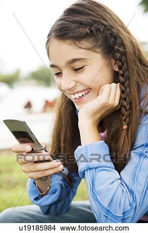 Picture - A young girl using a mobile phone. Fotosearch