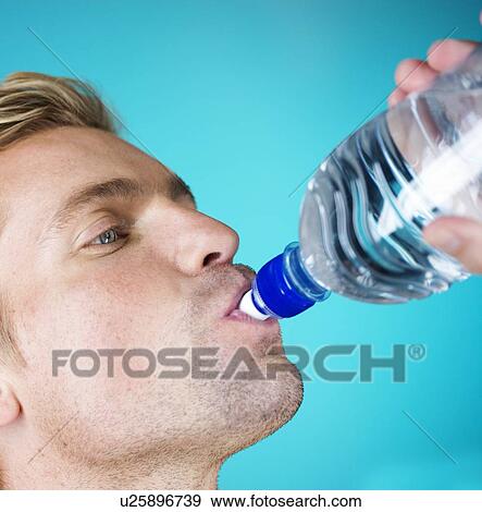 A young man drinking water from a bottle View Large Photo Image Stock Photo - A young man drinking water from a bottle. Fotosearch