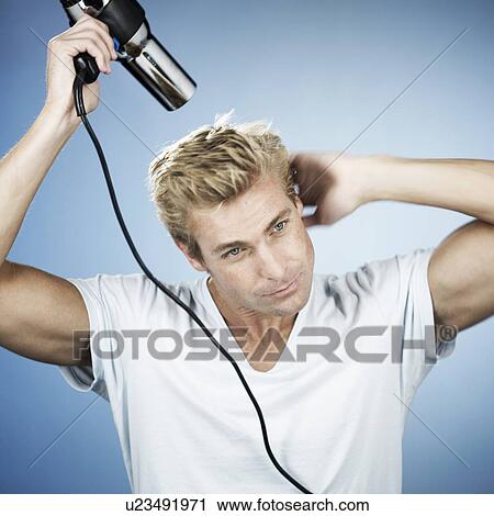 Stock Image - A young man drying his hair. Fotosearch