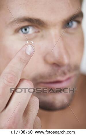 A young man inserting a contact lens View Large Photo Image Stock Image - A young man inserting a contact lens. Fotosearch