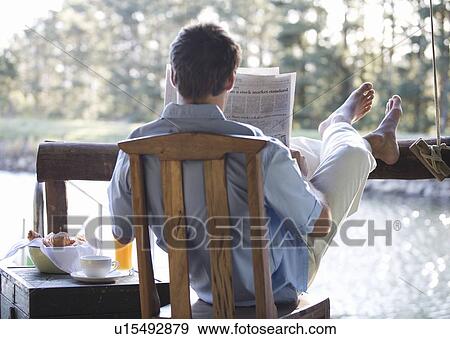 A young man reading the paper at breakfast View Large Photo Image Stock Photo - A young man reading the paper at breakfast. Fotosearch