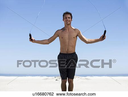 Stock Image - A young man skipping on a beach. Fotosearch