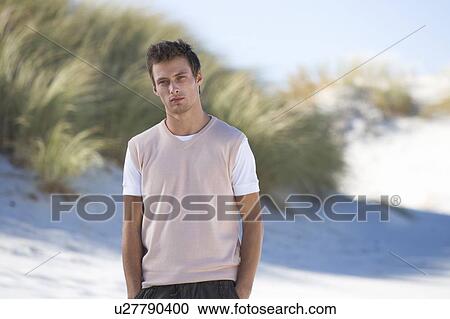 A young man standing on a beach View Large Photo Image Stock Image - A young man standing on a beach. Fotosearch