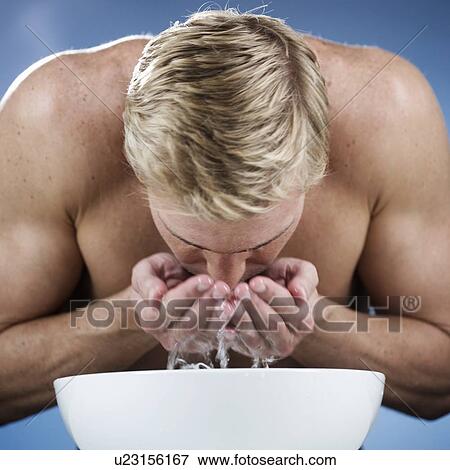 Stock Photo - A young man washing his face. Fotosearch