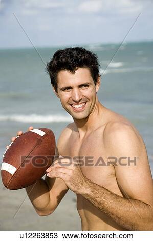 Stock Image - A young man with a ball on the beach. Fotosearch