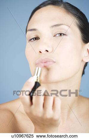 A young woman applying lipstick View Large Photo Image Stock Photography - A young woman applying lipstick. Fotosearch