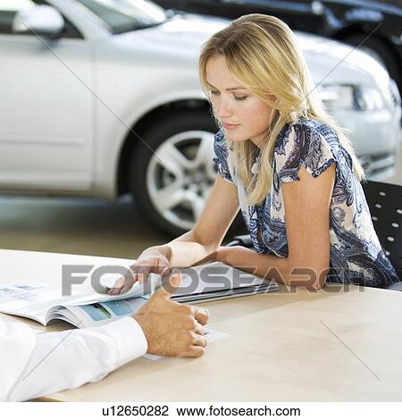 Stock Image - A young woman buying a new car. Fotosearch