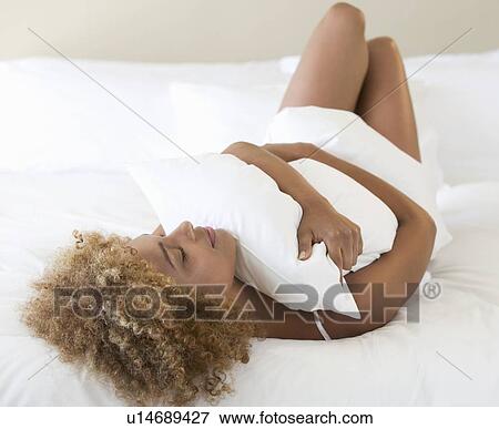 Stock Photo - A young woman hugging a pillow. Fotosearch