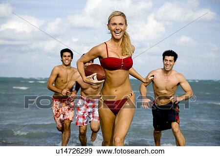 A young woman in a bikini being chased by three men View Large Photo Image Stock Photo - A young woman in a bikini being chased by three men. Fotosearch