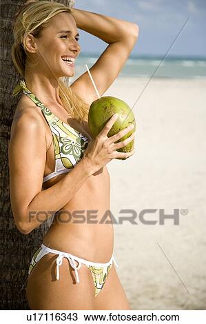 Stock Image - A young woman in a bikini standing on a beach. Fotosearch
