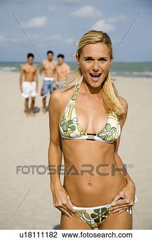 Stock Image - A young woman in a bikini with three male admirers. Fotosearch