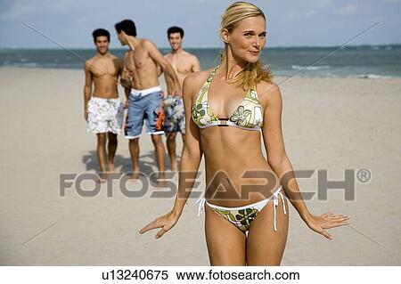 A young woman in a bikini with three male admirers View Large Photo Image Stock Photography - A young woman in a bikini with three male admirers. Fotosearch