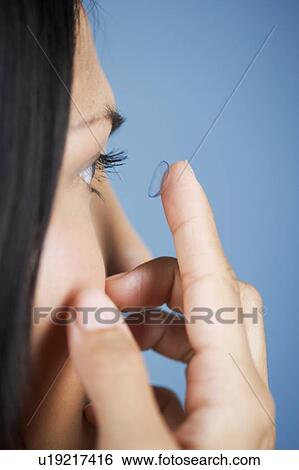 Stock Photograph - A young woman inserting a contact lens. Fotosearch