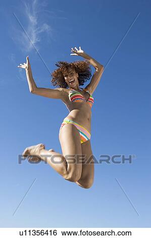 Stock Photograph - A young woman jumping. Fotosearch